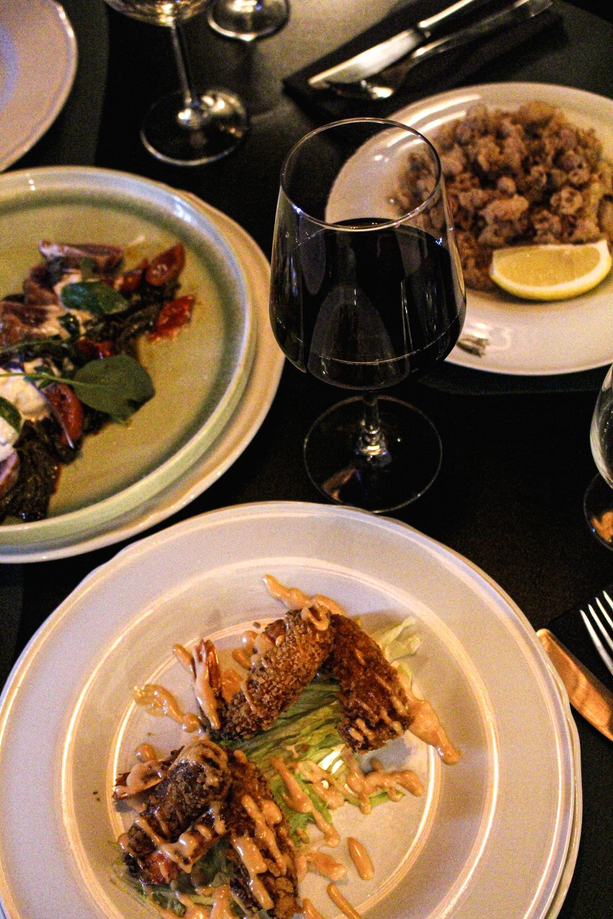Tavola apparecchiata con vino e piatti dell’osteria